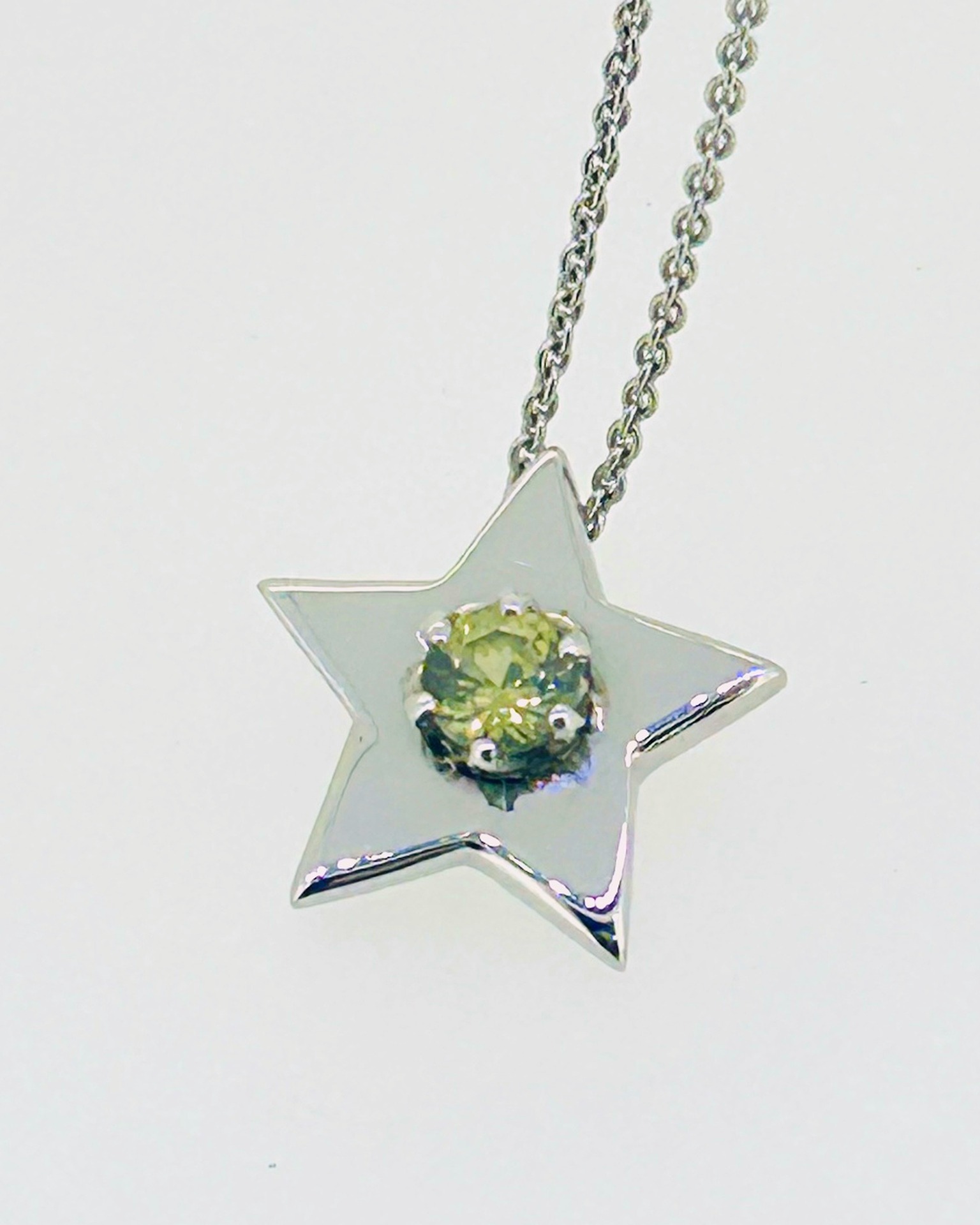 18-carat White Gold Star Pendant with Pale Yellow Sapphire, A star pendant in white gold with a pale yellow sapphire.